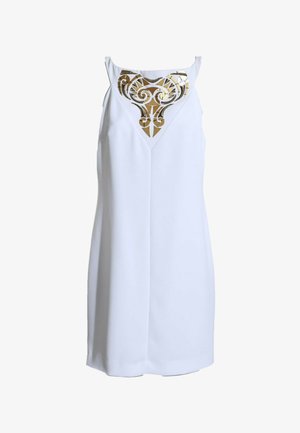 Robe blanche sans manches avec un décolleté en V ornée d'un motif géométrique et tourbillonnant doré sur la poitrine.