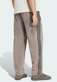 Grå bomullsblandade sweatpants med avslappnad passform, med svarta sidostickningar och synliga sömmdetaljer. Bärs med grå skor.