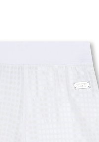 Pantalones cortos blancos de DKNY con una cinturilla lisa y un diseño de malla ligera con puntos, que tiene una pequeña etiqueta de la marca en un lado.