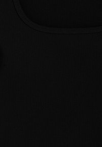 Camiseta negra de tirantes con cuello redondeado y textura suave. La tela presenta líneas verticales y un diseño ajustado.