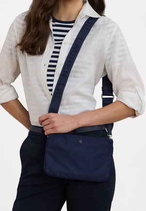 Sac bandoulière en tissu bleu marine avec une sangle texturée portant la marque « RL LAUREN ». Forme rectangulaire, fermeture zippée et détail du logo à l'avant.