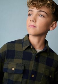 Groen en marineblauwe geblokte flanellen overhemd met een kraag, twee borstzakken en gouden knopen, met een zachte textuur en geruit patroon.