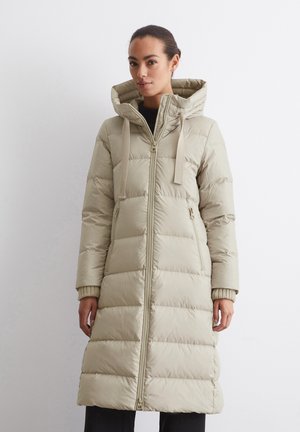 Beige nadolník s dlhým strihom, so zipsom vpredu, kapucňou a bočnými vreckami. Má textúrovanú látku a elastické manžety.
