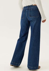 Breda mörk denimjeans med hög midja, med två bakfickor och en fransad fåll vid bensluten.