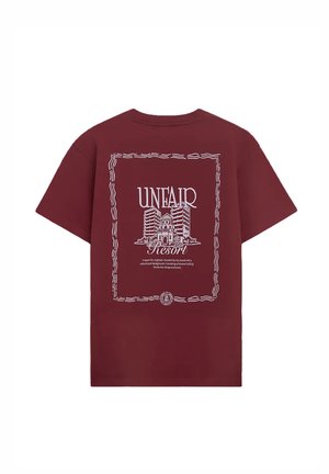 Bordeauxrotes T-Shirt mit weißer Linienzeichnung von Gebäuden, umrahmt von einem wellenförmigen Rahmen, und dem Text "UNFAIR Resort" auf dem Rücken.
