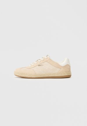 Beige suede sneaker with white striped textile panels, rubber sole, and woven jute accents. Features round toe and six eyelet lace-up design.