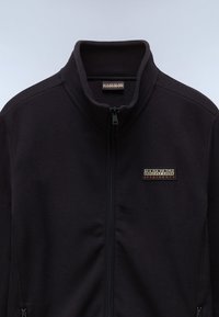 Black fleece jacket with a high collar, full front zipper, and logo patch on the chest. Soft texture and simple design.