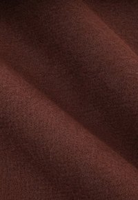 Brązowy filc z miękką, teksturowaną powierzchnią, ukazujący subtelne różnice w odcieniu i głębokości na fałdach i zagięciach.