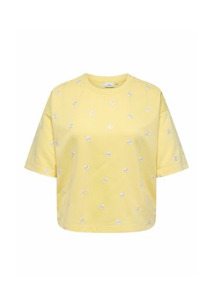 T-shirt court jaune à manches courtes avec de petites impressions de marguerites blanches dispersées sur le tissu.