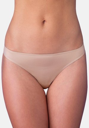 Kobieta w bezszwowej bieliźnie w kolorze nude z niskim stanem, ukazująca środkową część tułowia i górną część ud na białym tle.