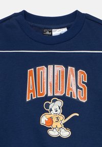 Μπλε σκούρο φούτερ από βαμβάκι, με μεγάλο πορτοκαλί γράμμα "ADIDAS" με υφή δίχτυ και καρτούν χαρακτήρα που κρατάει μπάλα μπάσκετ.