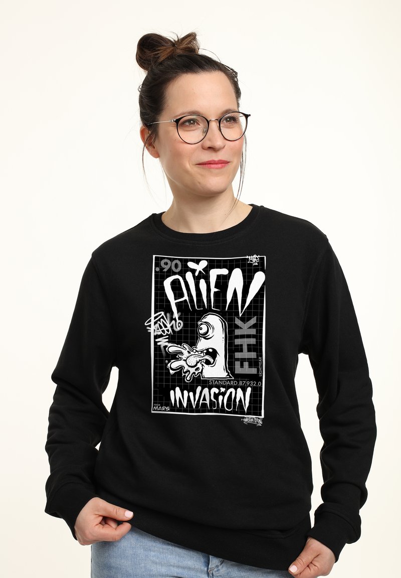 Felpa nera a maniche lunghe con una grande grafica bianca che raffigura un alieno in stile cartone animato e il testo "ALIEN INVASION".