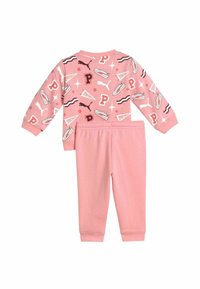 Rosa tvådelad outfit bestående av en långärmad topp med tryck av sneakers och logotyper, samt matchande byxor med elastisk midja. Mjuk bomullsmaterial.