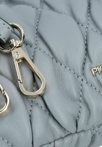 Borsa a tracolla in pelle grigia trapuntata con un'applicazione in metallo dorato e dettagli in cucitura, che mette in mostra una superficie testurizzata con una leggera lucentezza.