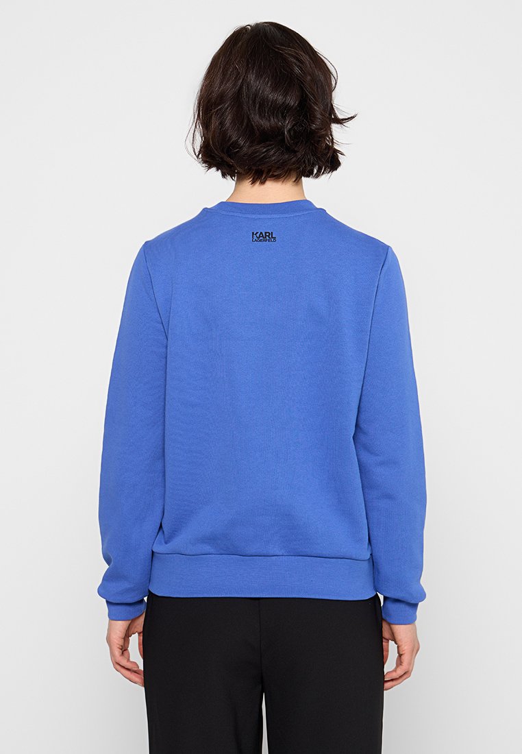 Sudadera azul con cuello redondo, mangas largas y puños acanalados. Pequeño logo en la parte superior de la espalda. Tejido suave de mezcla de algodón.