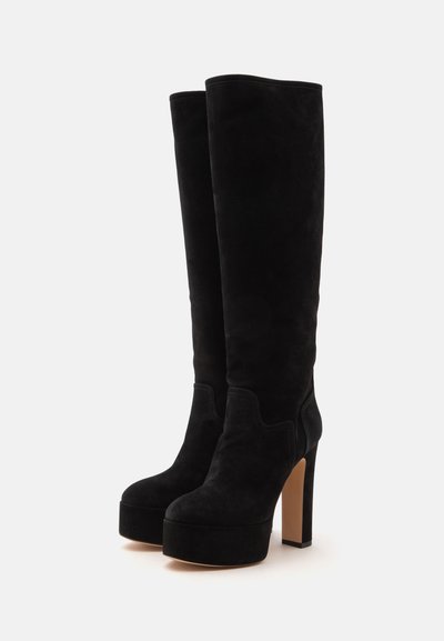 Bottes plateformes hautes en daim noir avec talons hauts épais et bouts arrondis, présentées côte à côte sur fond blanc.