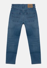 Jeans de mezclilla azul con cintura alta, corte slim-fit, dos bolsillos traseros y un parche de cuero en la cintura con el logotipo de la marca.