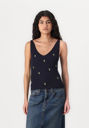 Camiseta de tirantes de rayas en color navy con escote en V, adornada con pequeños diseños de limones amarillos bordados. Combinada con una falda de mezclilla.