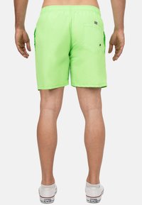 Felgroene zwembroek met een elastische tailleband, zijzakken en een achterzak met knoopsluiting. Glad, lichtgewicht materiaal.