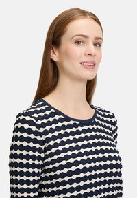 Marlit blau-weiß gestreiftes Langarmoberteil mit wellenförmigem strukturiertem Muster, rundem Halsauschnitt und einfarbigem navyblauen Besatz entlang des Kragens.