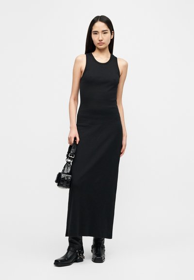 Μαύρο μακρύ φόρεμα με ριμπ ύφανση, μανίκια χωρίς μανίκια, στρογγυλή λαιμόκοψη και εφαρμοστή σιλουέτα. Στυλιζαρισμένο με υφασμάτινο μικρό τσαντάκι και μαύρα μποτάκια αστραγάλου.