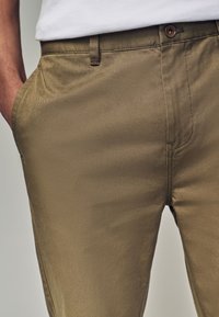 Khaki-byxor i texturerat tyg med slim fit, som har framfickor och en enda knappknäppning i midjan.