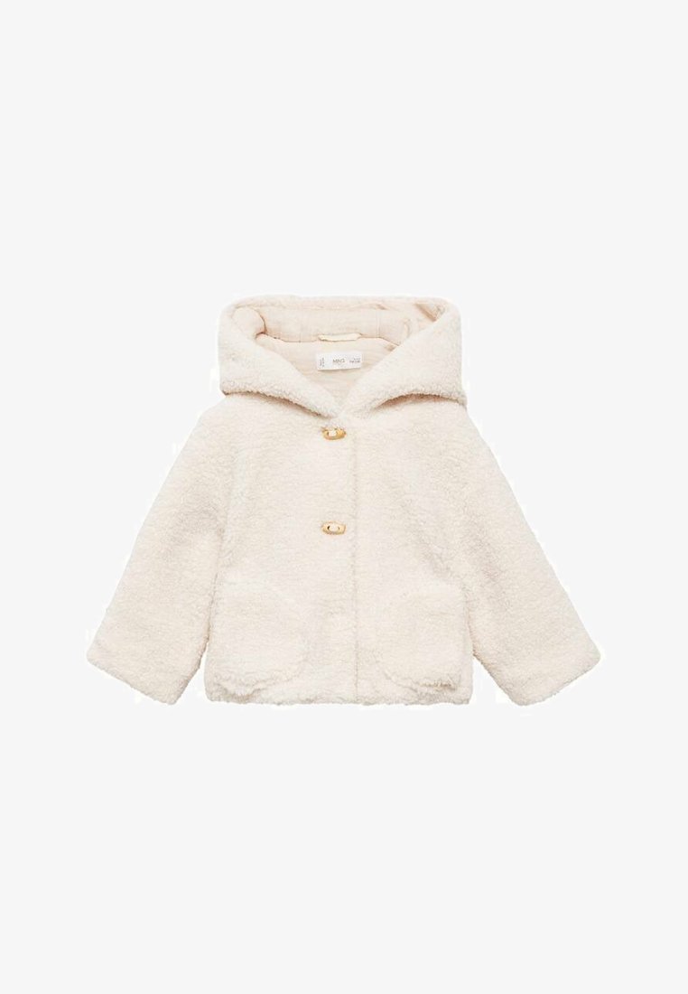 Kremvärinen tekoturkis takki huoodilla, jossa on kaksi etutaskua ja kultaiset napit. Takissa on teksturoitu, pehmeä kangas ja lyhyet hihat.