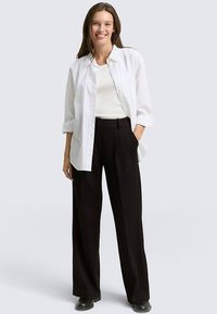 White button-up shirt layered over a plain white top, paired with black pinstriped wide-leg trousers, featuring a relaxed fit and smooth texture.