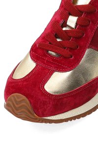 Roter Wildledersportschuh mit goldenen metallischen Akzenten, strukturierten Schnürsenkeln und einer gemusterten Gummisohle. Abgerundete Zehenpartie mit gepolstertem Zwischensohle.