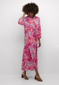 Vibrant roosa maxi kleit paisley mustriga. Pikad varrukad, mugav lõige, kokkutõmmatud talje ja kerge kangas. Ühendatud pruunide kontsakingadega.