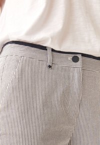 Pantalons rayés avec une taille marine, dotés d'un bouton de fermeture, et d'un tissu doux et texturé avec des rayures alternées claires et foncées.