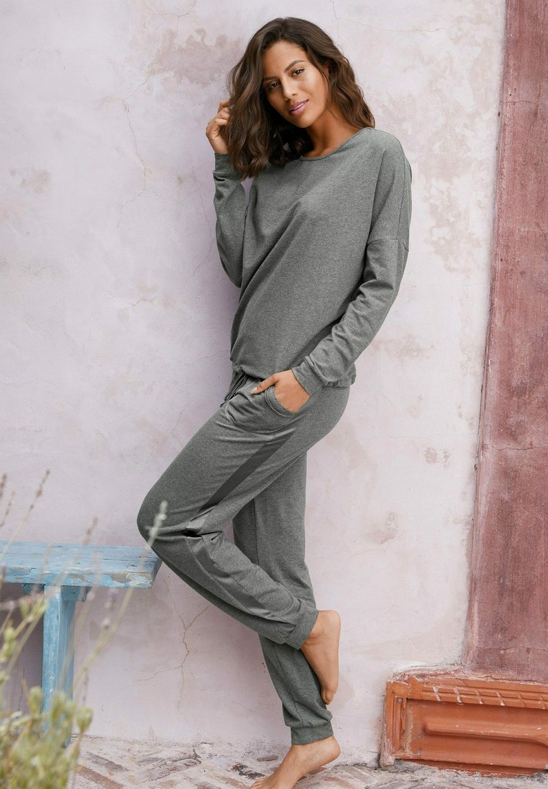 Gray loungewear set featuring a long-sleeve top and jogger pants. Soft fabric, relaxed fit, side pockets, and contrasting side stripes.