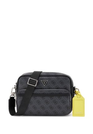 Čierna crossbody taška s monogramom, so zipsom, nastaviteľným popruhom a žltou etiketou. Obsahuje kovové kovania a hladký povrch.