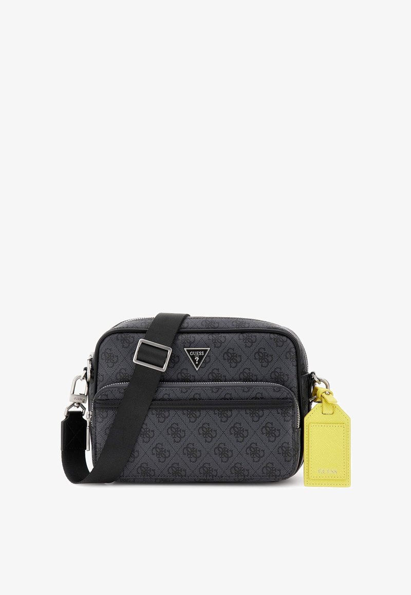 Borsa crossbody nera con monogramma, chiusura a zip, tracolla regolabile e etichetta gialla. Presenta componenti in metallo e una texture liscia.