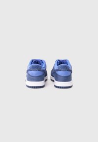 Blå Nike-sneakers med en slät läderöverkonstruktion, vadderad krage och vit mellansula. Har en strukturerad gummisula och logotyp på hälen.