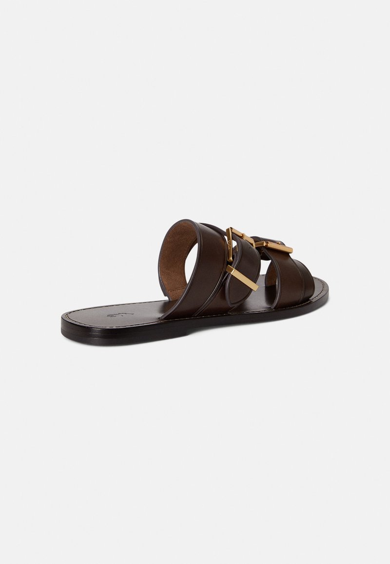Brown leather slide sandal with two overlapping straps and gold-tone hardware accents. Flat sole with minimal tread and smooth texture.