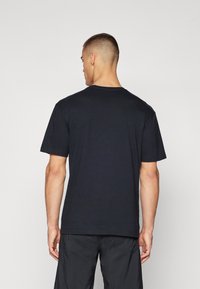 Sort kortærmet t-shirt lavet af bomuld, med rund hals og en afslappet pasform. Stofoverfladen virker glat med minimale sømme.