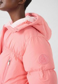 Giacca imbottita rosa con cappuccio, vita elastica e toppa con logo sulla manica. Il materiale sembra liscio con una leggera lucentezza.
