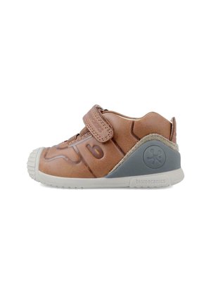 Zapatilla de cuero marrón con una cinta de velcro, suela de goma y suaves acentos grises. Presenta un diseño moldeado en la parte delantera y un logo de marca en el talón.