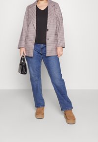 Rutig kavaj i ljus rosa och brunt, matchad med en svart topp och blå jeans. Bruna platåstövlar och en liten svart handväska fulländar looken.