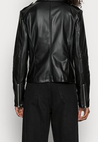 Schwarze, taillierte Kunstlederjacke mit strukturiertem Kragen, seitlichen Reißverschlusstaschen, strukturierten Ellbogenakzenten und diagonalen Steppnähten.