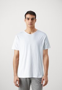 T-shirt in cotone azzurro chiaro con scollatura a V, maniche corte e vestibilità rilassata. Presenta un piccolo logo sul lato sinistro vicino all'orlo.