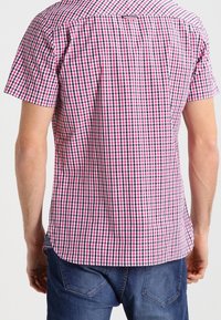 Camicetta a maniche corte a quadri nei toni di rosa e blu navy, con colletto button-down e vestibilità slim. Il tessuto presenta un motivo a rete con una sottile texture.