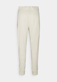 Lichtbeige sportieve joggers met een elastische tailleband, taps toelopende pijpen en ribbelmanchetten. Gladde stof met minimale stikdetails.
