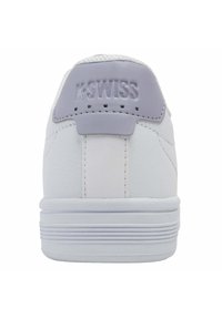 Baskets K-Swiss blanches avec un onglet de talon lavande clair et un logo en relief. Tige synthétique lisse, nez rond et semelle texturée avec des lignes horizontales.