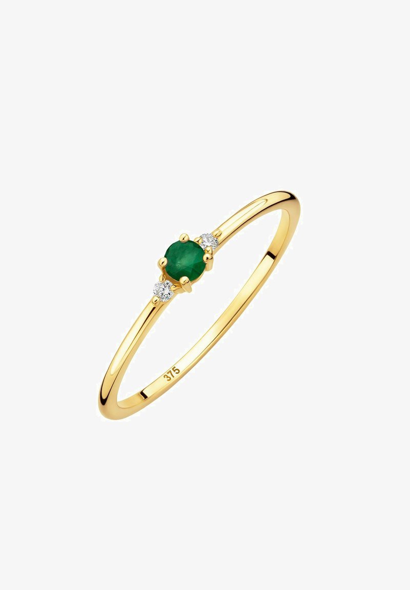 Anello in oro con un'elegante smeraldo verde centrale tondo, affiancato da due piccoli diamanti trasparenti, e una banda liscia e lucida.