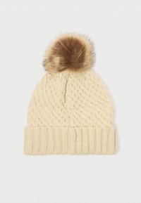 Knitted beige beanie with a textured pattern and a brown faux fur pom-pom on top; features a ribbed cuff for a snug fit.
