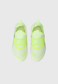 Baskets jaunes fluo à enfiler avec un dessus en maille, sangle élastique arborant "NIKE," et superpositions arrondies. Semelle blanche avec grip texturé.