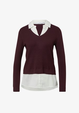 Ciemnofioletowy sweter z teksturą w serek, nałożony na białą koszulę z długimi rękawami i zaokrąglonym hemem.