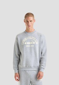 Felpa grigia in cotone con scollo rotondo, caratterizzata da una stampa bianca del logo e polsini e orlo a costine. Abbinata a pantaloni coordinati.